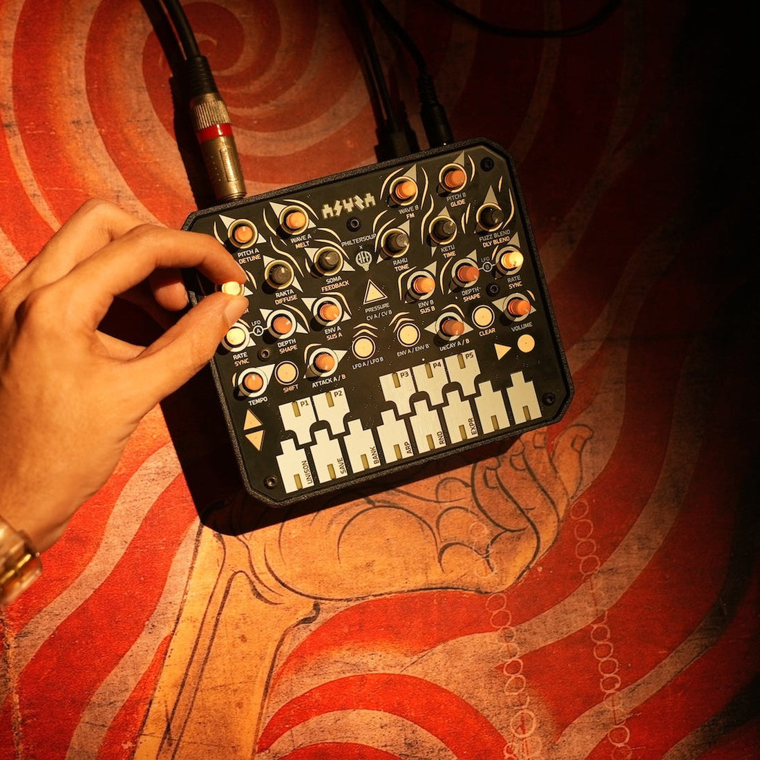 Animal Factory Amplification Asura, hand adjusting a knob with cables patched in