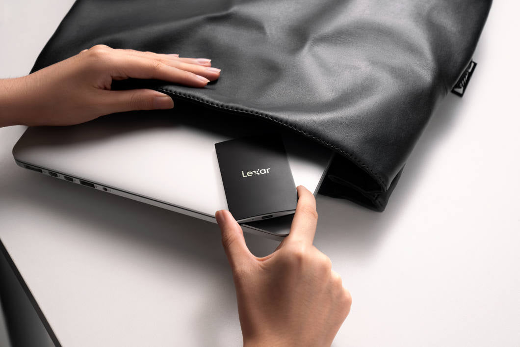 Lexar SL500 portable SSD external drive with sleek black design, shown on a wooden surface with digital devices.