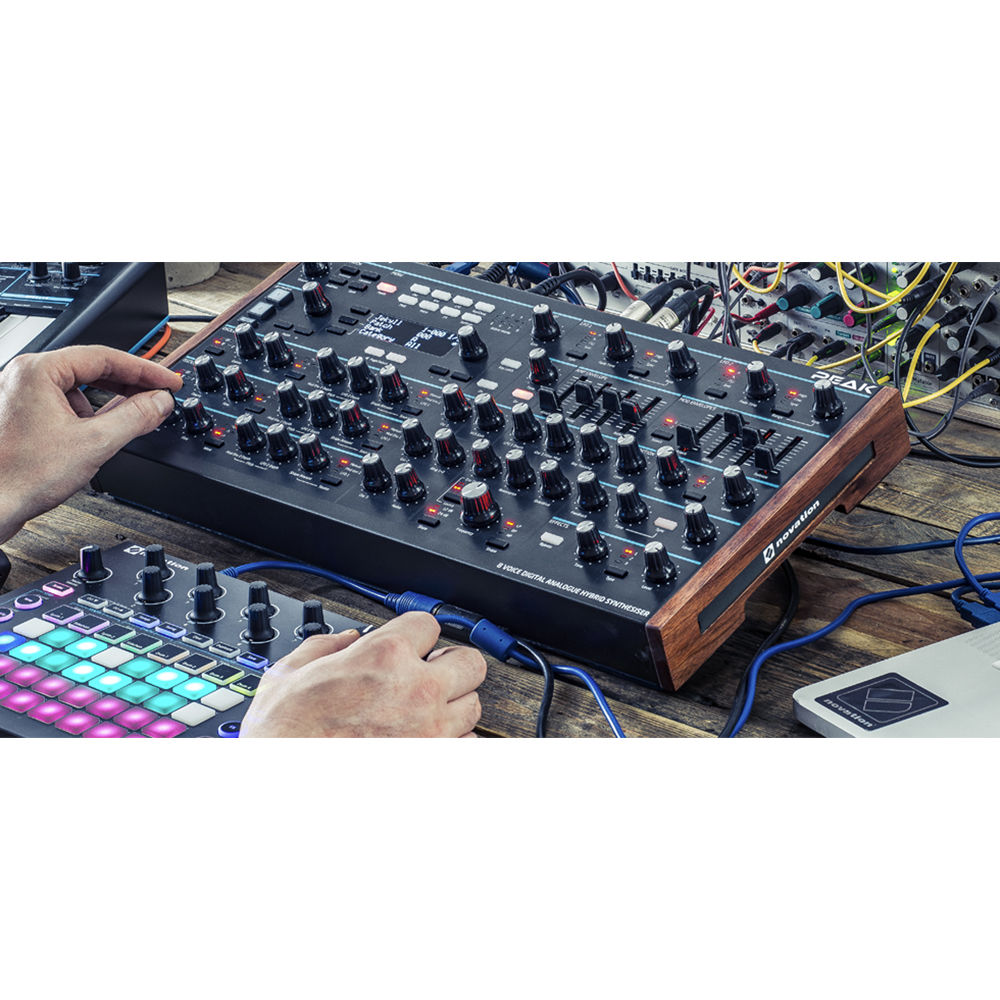 Novation Peak synthesizer with a sleek black control panel, multiple knobs, and digital display showing various sound settings.