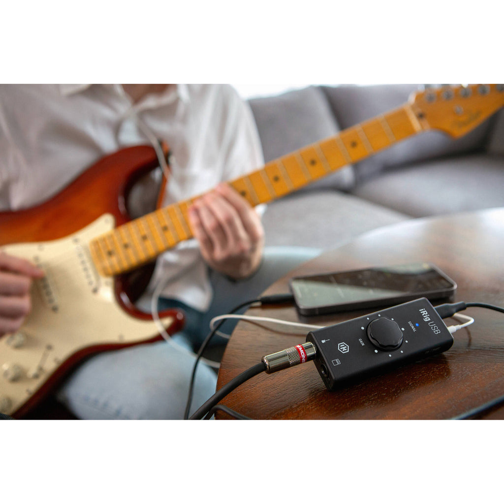 IK Multimedia iRig USB audio interface connected to a computer, showing input and output ports on a compact device.