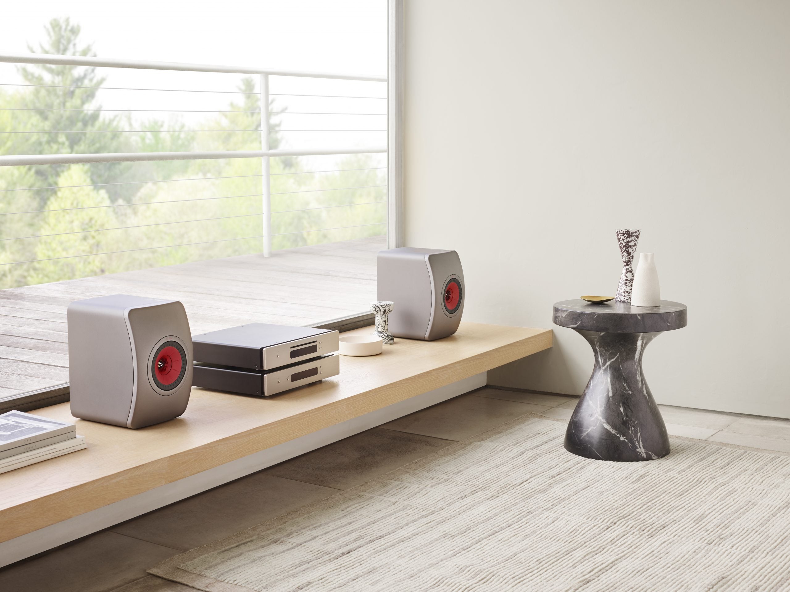 KEF LS50 Meta passive bookshelf speakers in titanium grey, shown on a side shelf setup with detailed driver and sleek design.
