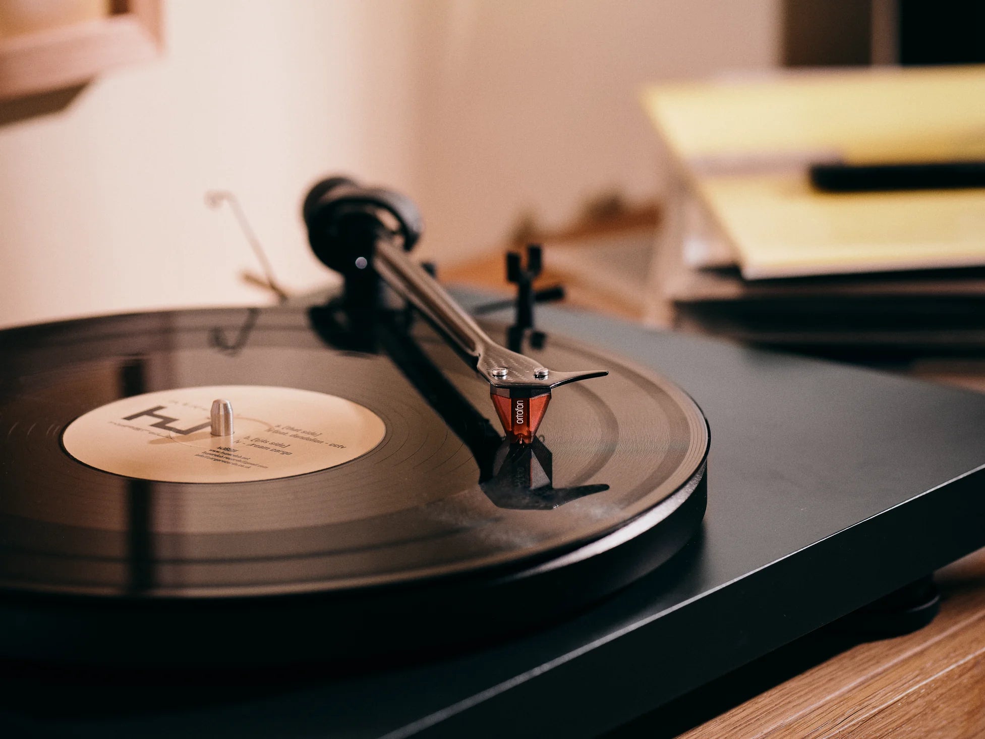 Ortofon 2M Red turntable cartridge with red stylus and body, shown mounted on a turntable for high-quality audio playback.