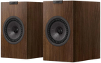 KEF Q3 Meta passive bookshelf speakers shown in a home audio setup with black cabinets and silver accents.