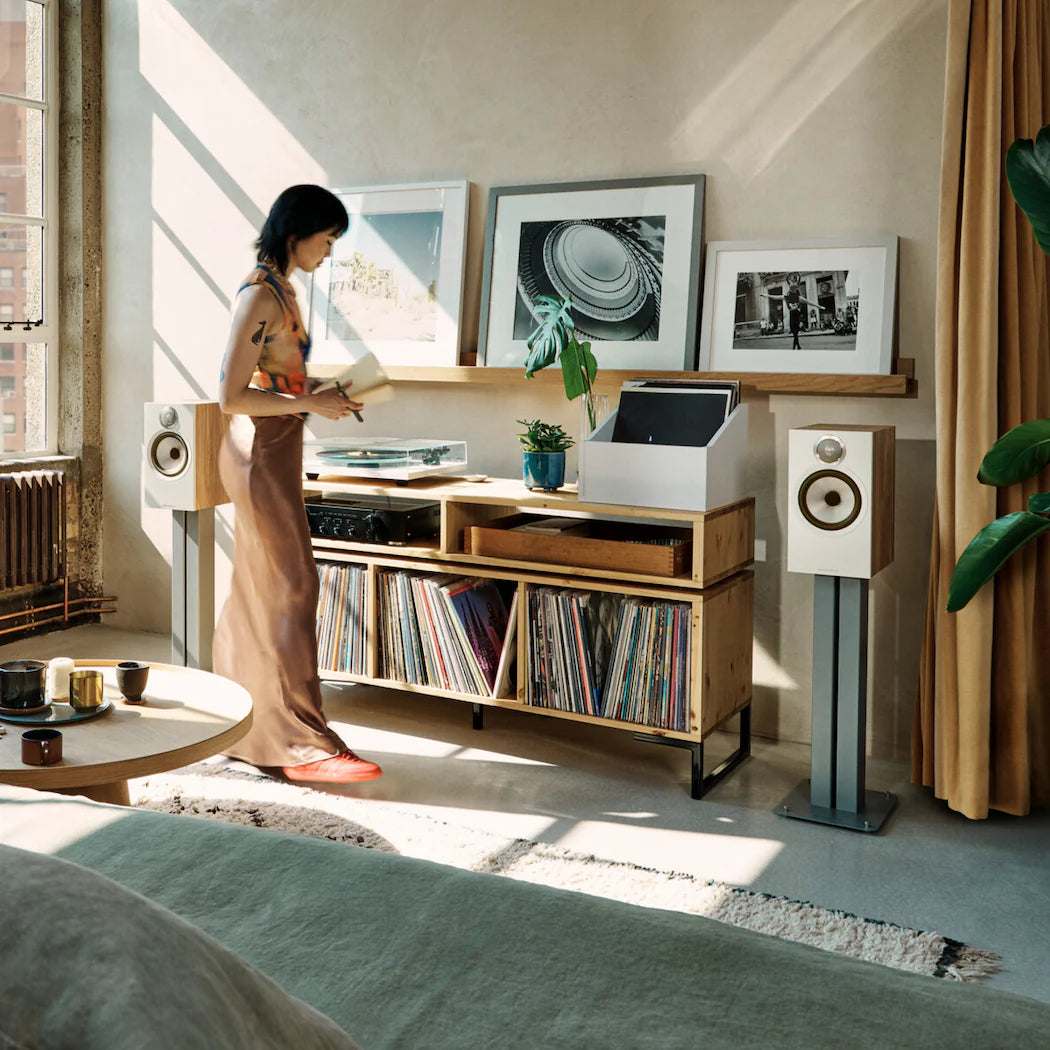 Bowers & Wilkins 606 S3 passive bookshelf speakers in oak finish, shown in a stylish home audio setup.