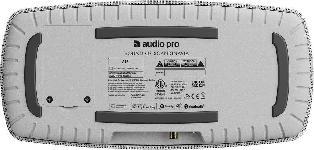 Audio Pro A15 portable speaker shown outdoors, compact design with fabric grille and control buttons on top.