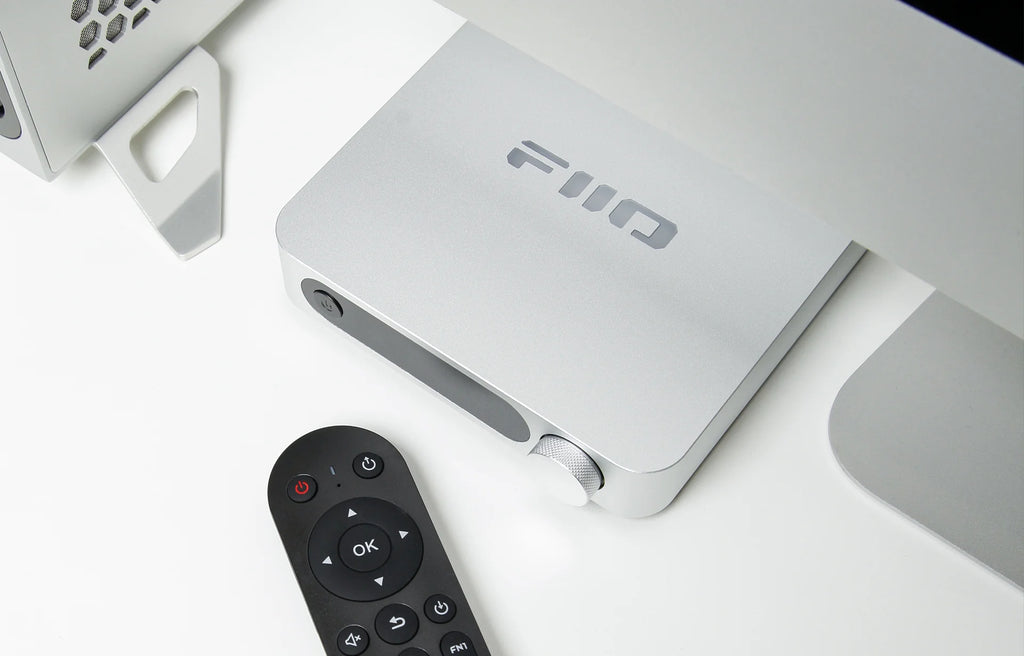 FiiO SR11 music streamer device with sleek black design and buttons on top, connected to audio cables and components.