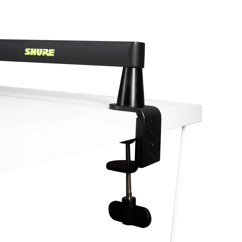 Shure SH-BROADCAST2 broadcast microphone arm mounted on a desk, adjustable with sleek metal design and cable management features.
