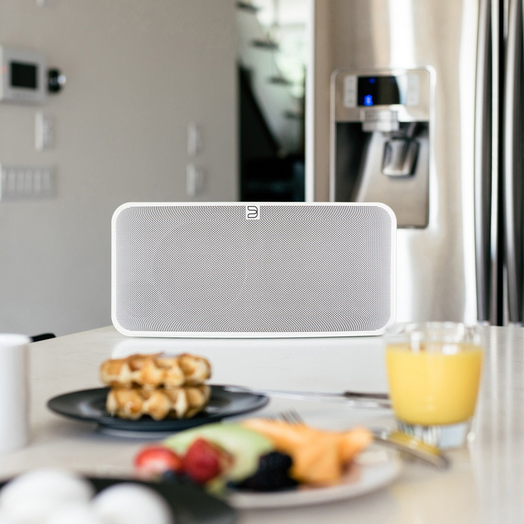 Close-up of Bluesound Pulse 2i wireless speaker in white, showing its sleek front design and control buttons.