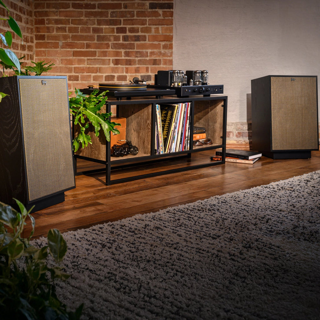 Pair of Klipsch Heresy IV floorstanding speakers in black ash flanking a record player on a media console.