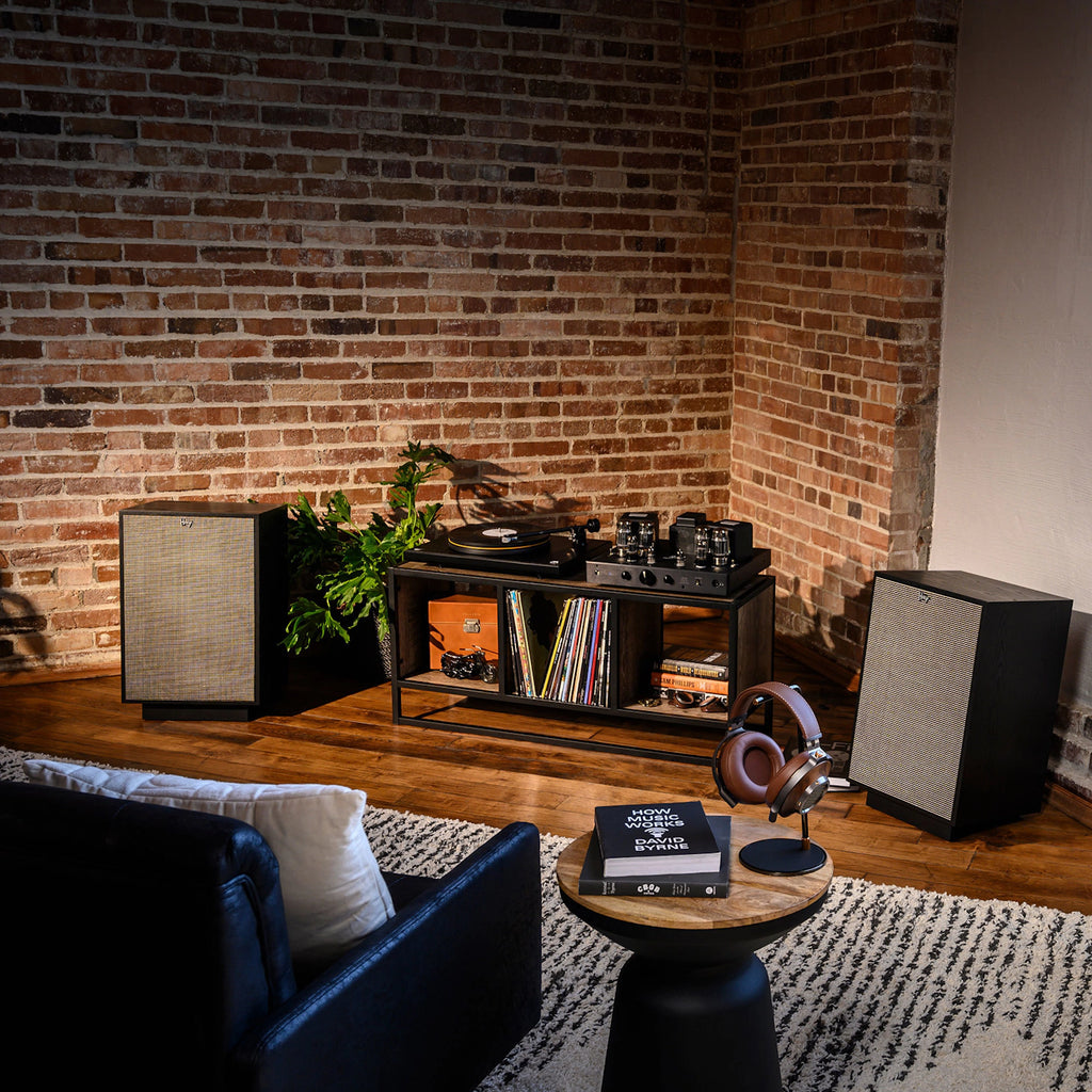 Klipsch Heresy IV floorstanding speakers next to a turntable, showcasing sleek black speaker design with wooden accents.