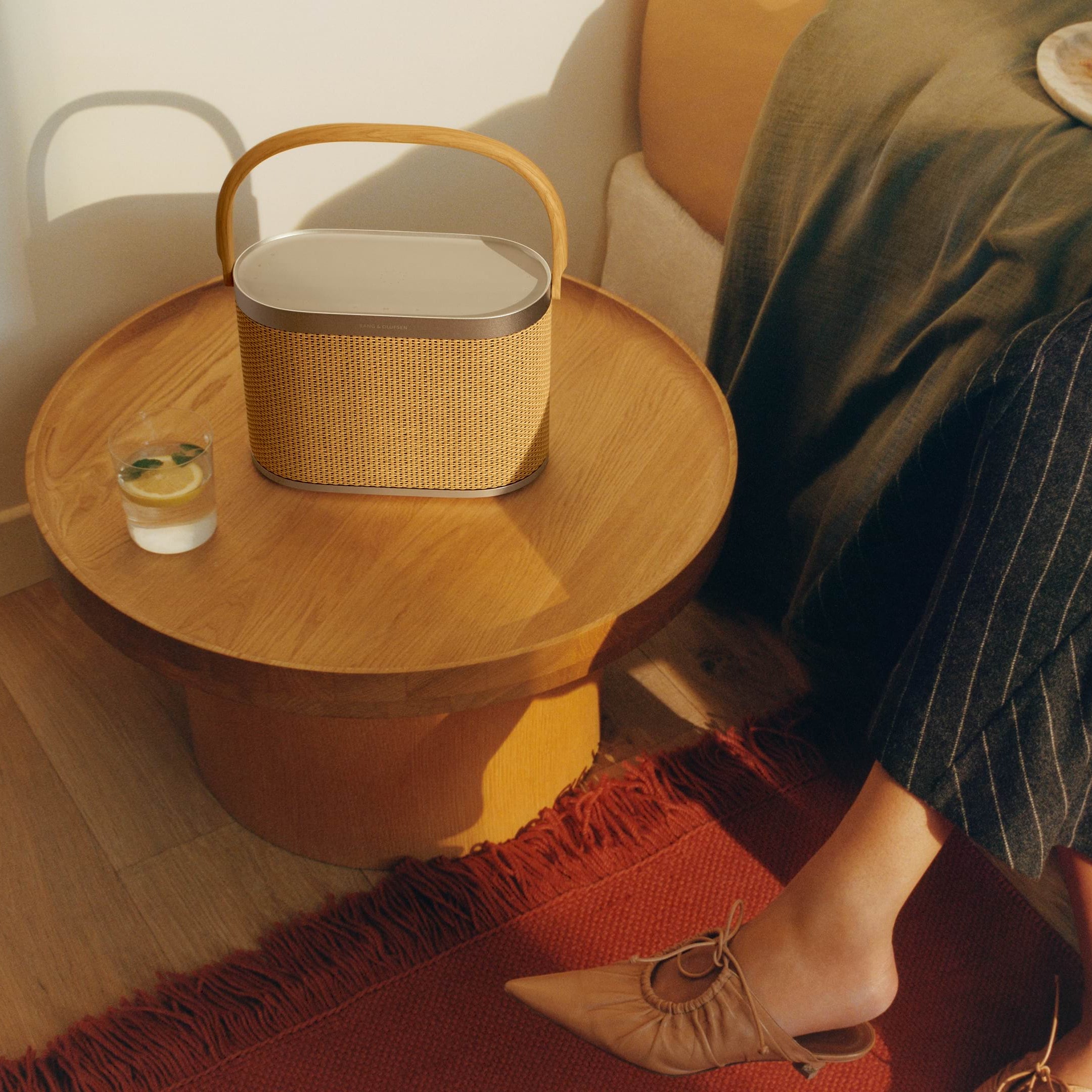 Bang & Olufsen Beosound A5 portable speaker in a stylish living room setting, showcasing its sleek design and fabric covering.