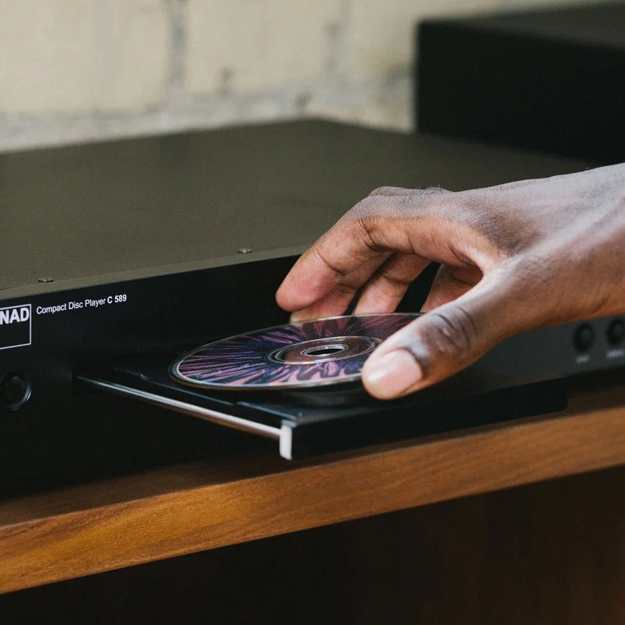 NAD C 589 CD player with hand adjusting controls, close-up view showing front panel and disc tray.