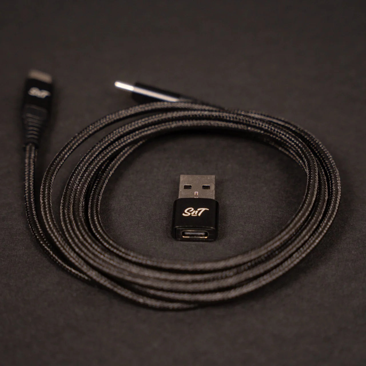 Sim'n Tonic Nome II MIDI interface with rolled USB cable and adapter, showcasing the compact design and connectivity options.