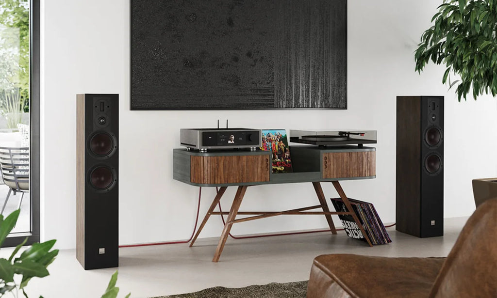 DALI Opticon 6 MK2 passive floorstanding speakers in a living room setting, showcasing their sleek design and speaker grille.