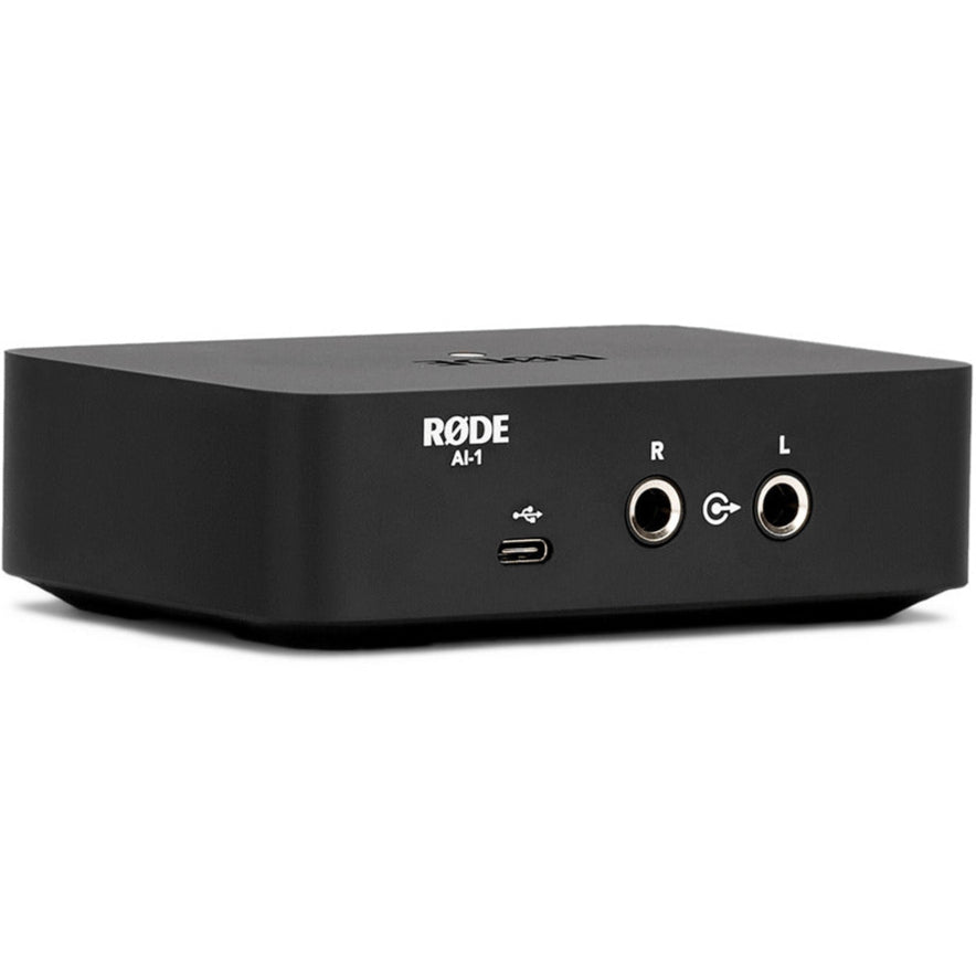 Rode AI-1 audio interface shown from a three-quarter left back angle, featuring input and output ports on a sleek black device.
