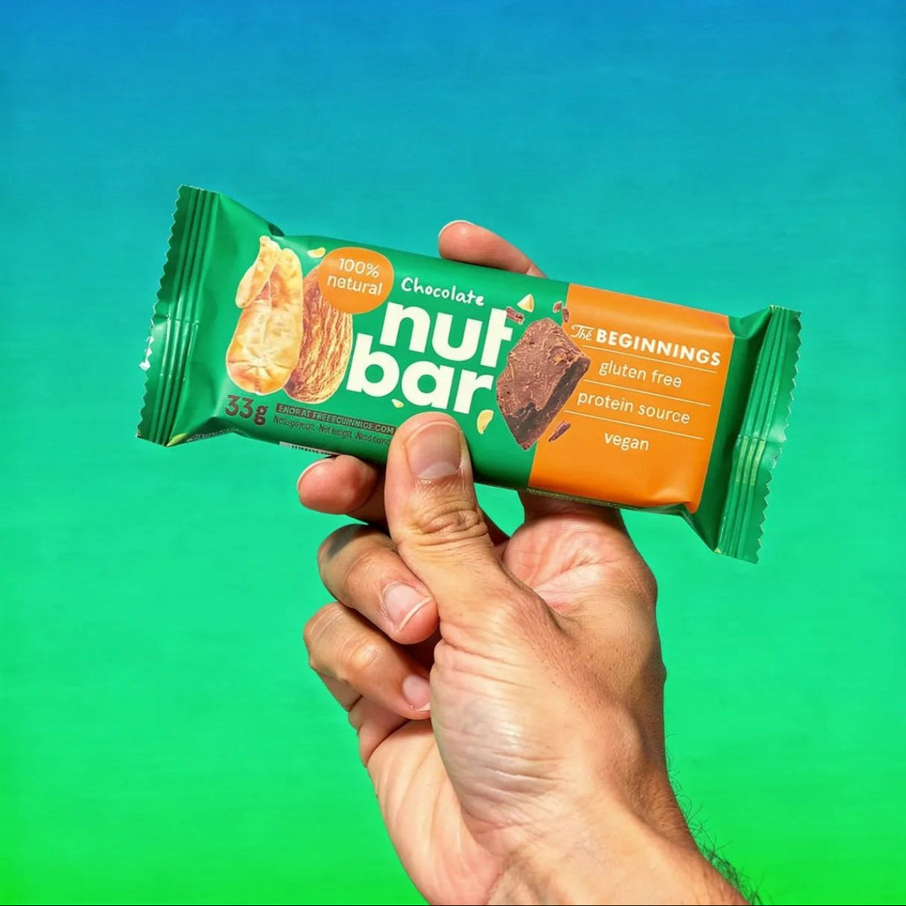 Hand holding a Nutbar against a gradient blue to green background