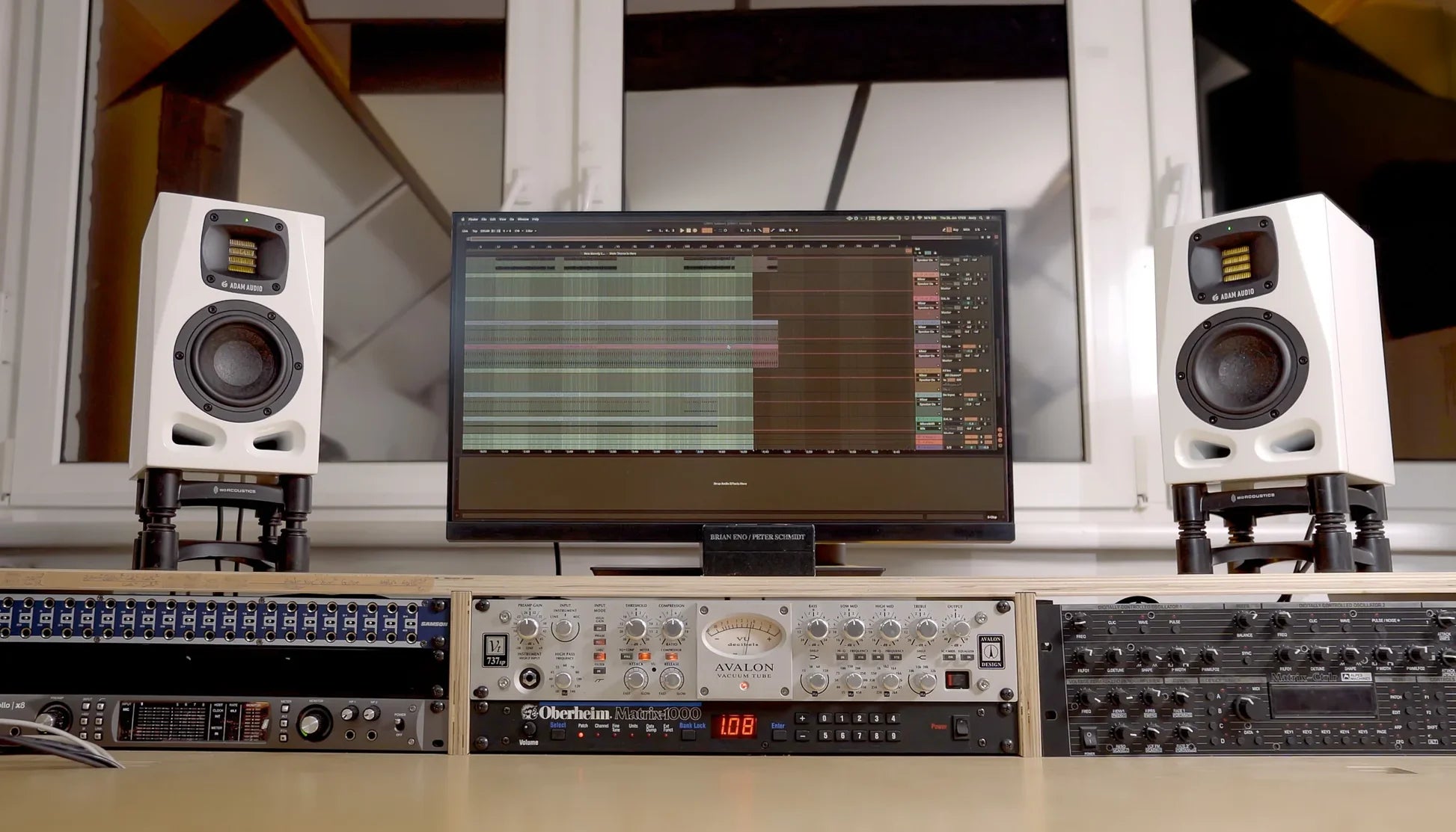 Pair of Adam Audio A4V active nearfield studio monitors shown on a desk in a limited edition 25th anniversary lifestyle image.