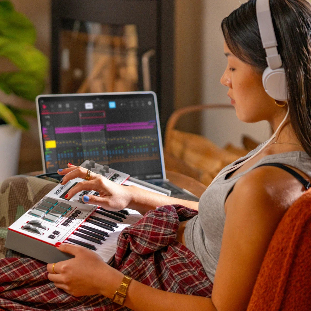 Akai Professional MPK Mini Plus II on the lap of a producer wearing headphones