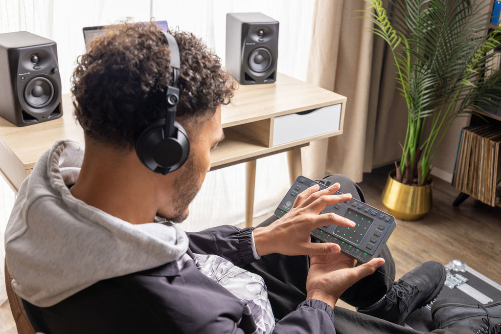 AlphaTheta ChordCat DJ pad controller, man holding device with headphones.