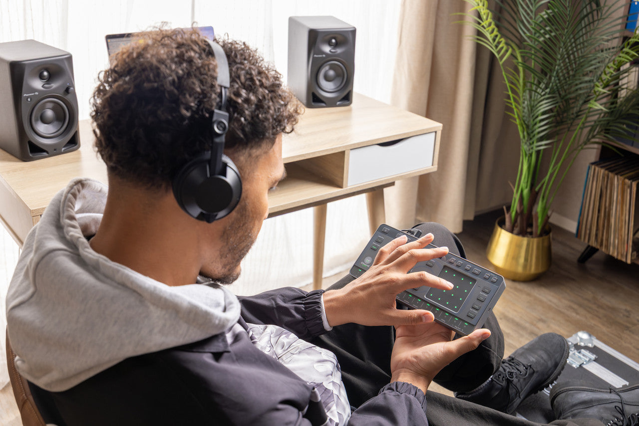 AlphaTheta ChordCat DJ pad controller, man holding device with headphones.