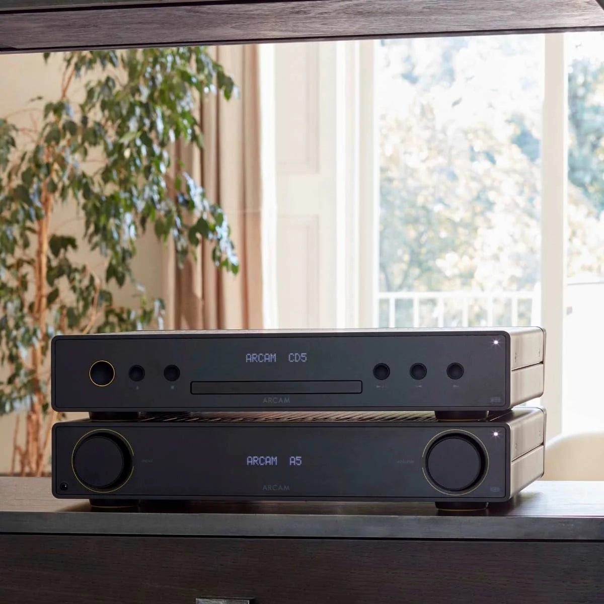 Arcam A5+ stereo amplifier shown in a lifestyle setting, featuring sleek design and controls for high-quality audio performance.