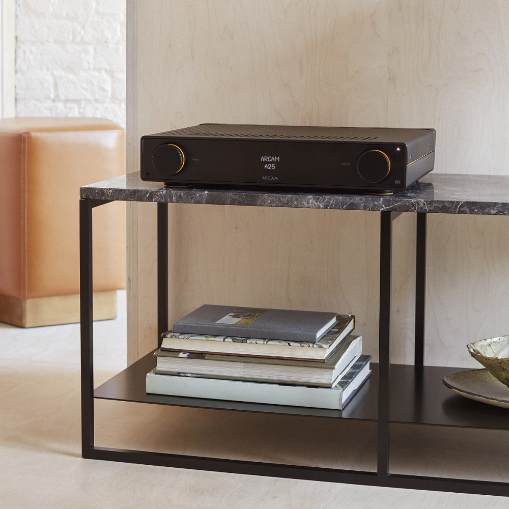 Arcam A25+ stereo amplifier showing front panel with control knobs and display, black finish, compact design, Arcam branding visible.
