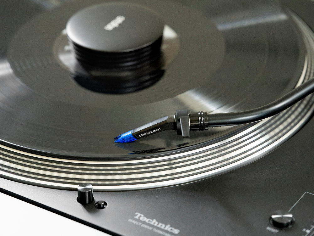 Ortofon Concorde Music Blue turntable cartridge mounted on Technics turntable, showcasing sleek blue design and stylus.