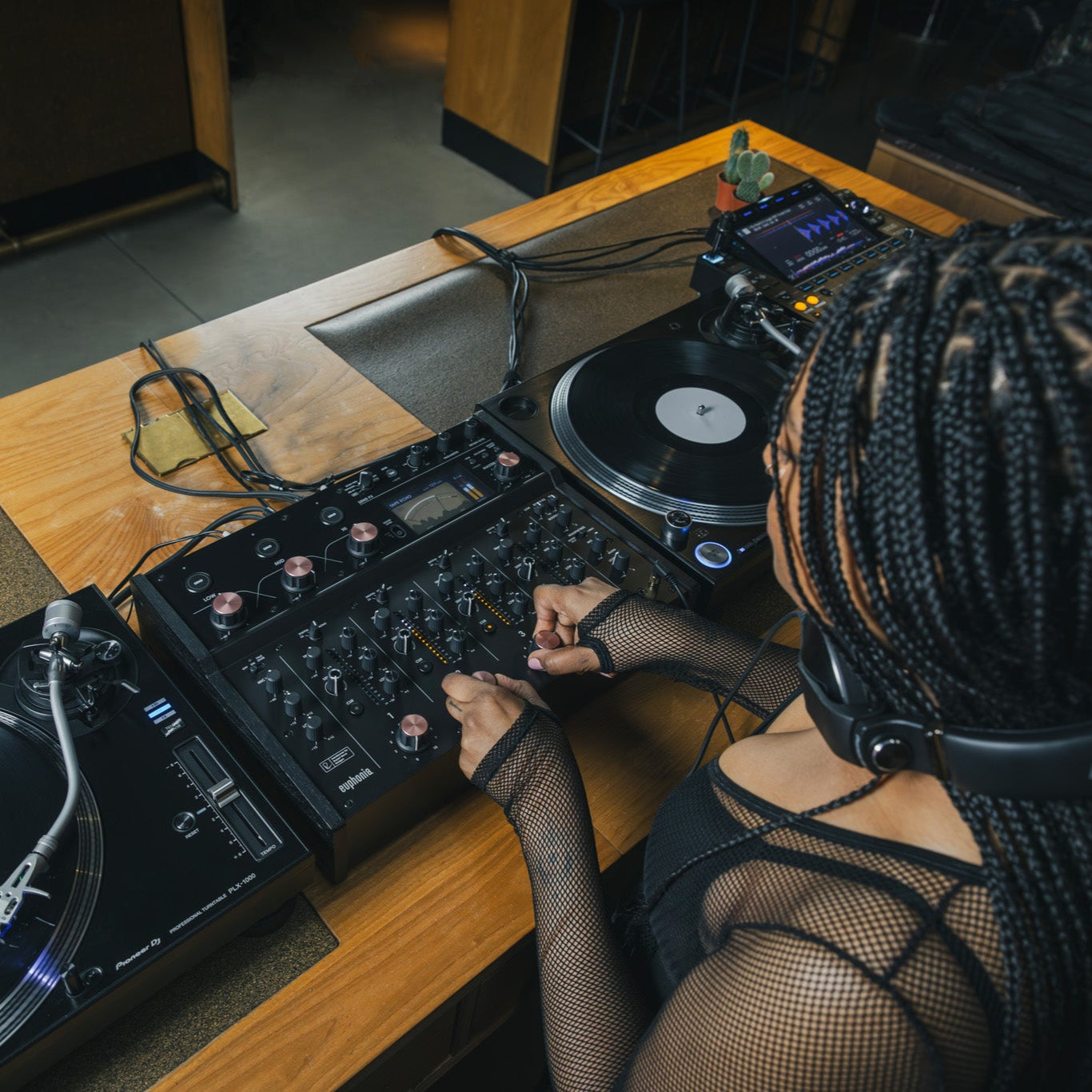 AlphaTheta Euphonia DJ mixer shown in a lifestyle setting with controls, knobs, and sleek design features.