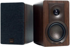 DALI Kupid passive bookshelf speakers shown in a modern living room setting, highlighting their sleek black design and compact size.