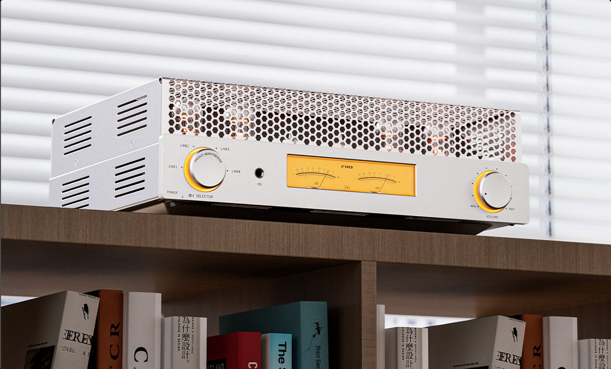 FiiO EA13 in silver on a bookshelf next to a stack of books