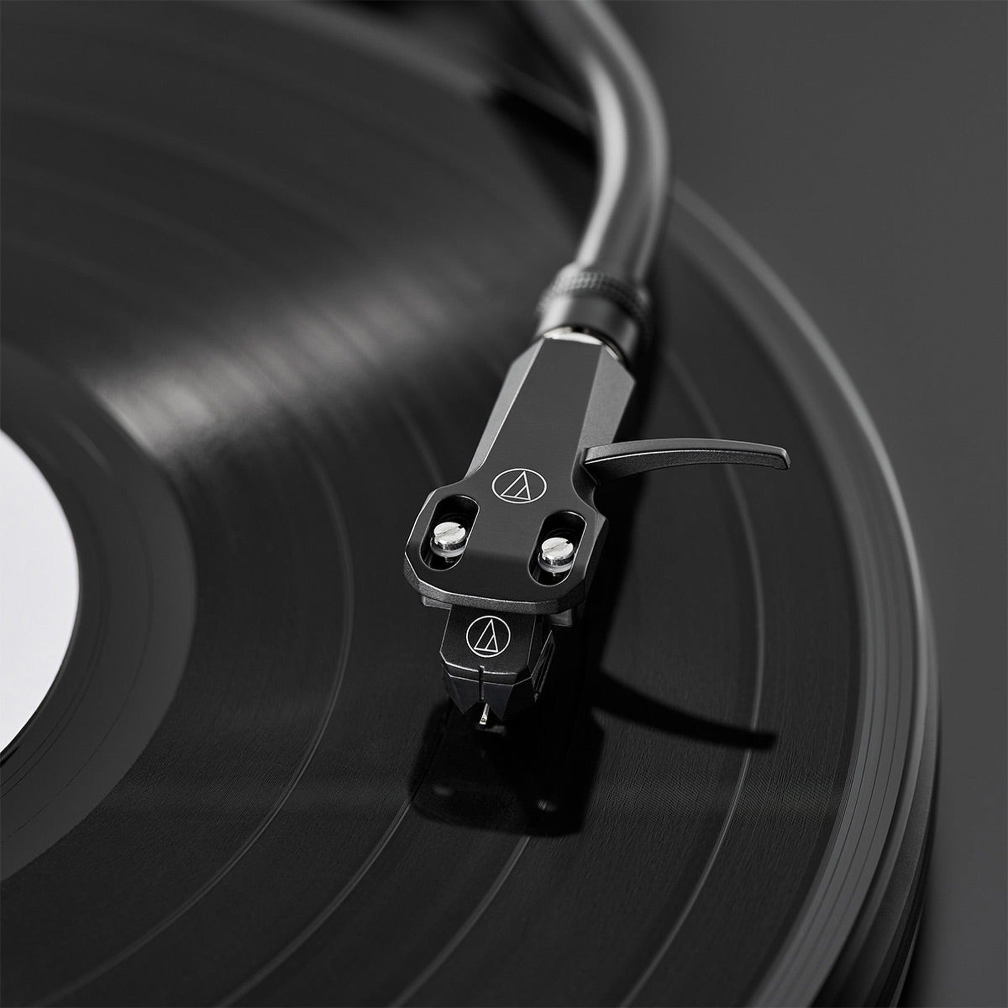 Audio-Technica AT-VM95EBK MM phono cartridge mounted on a turntable, showcasing its black body and stylus for high-quality audio playback.