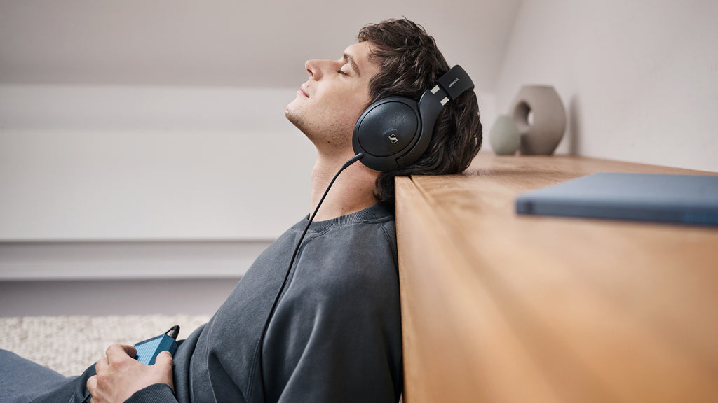 Sennheiser HD 620S headphones shown on a desk with headphones resting on a stand, highlighting their sleek design and comfortable fit.