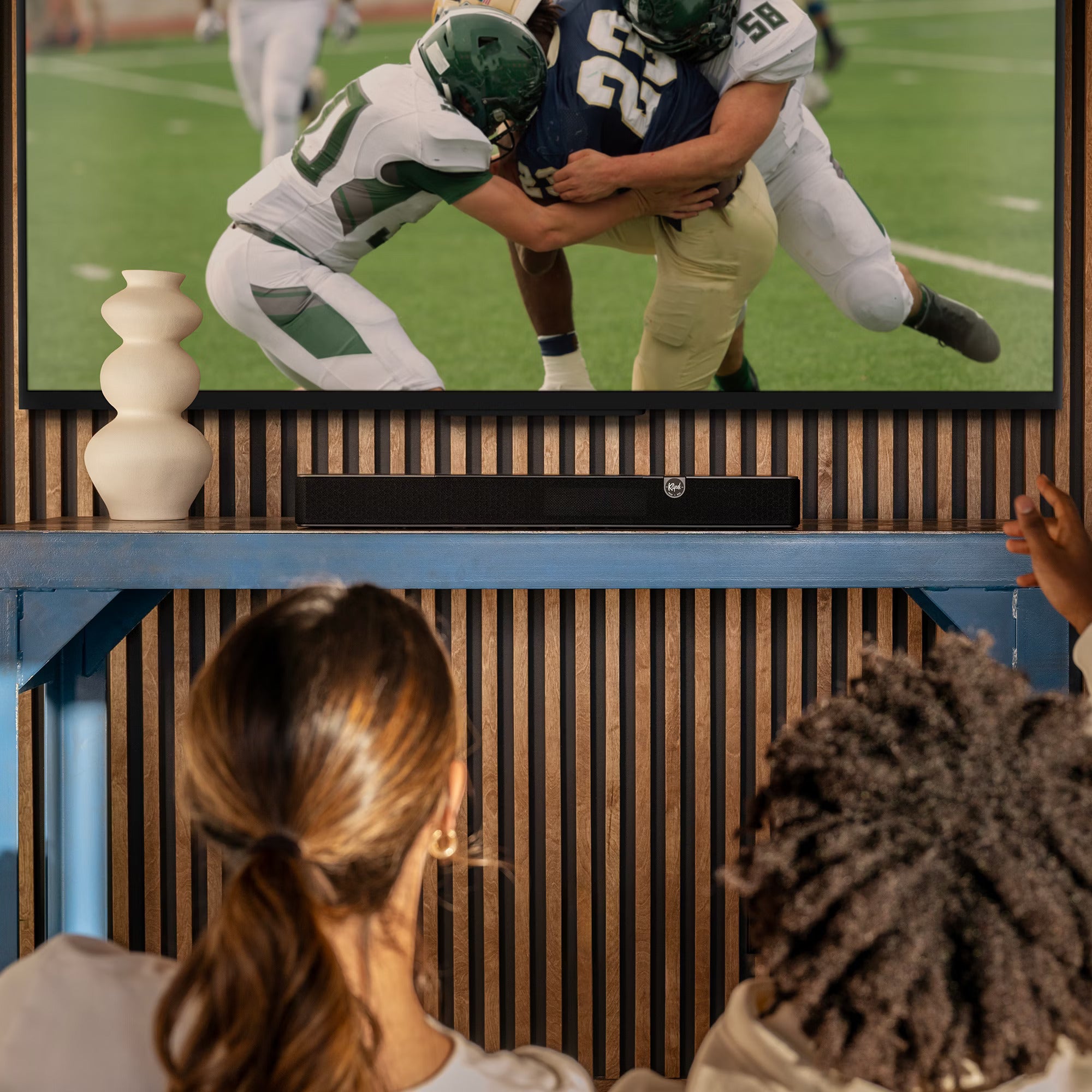 Klipsch Flexus Core 100 soundbar, on stand under TV football game.