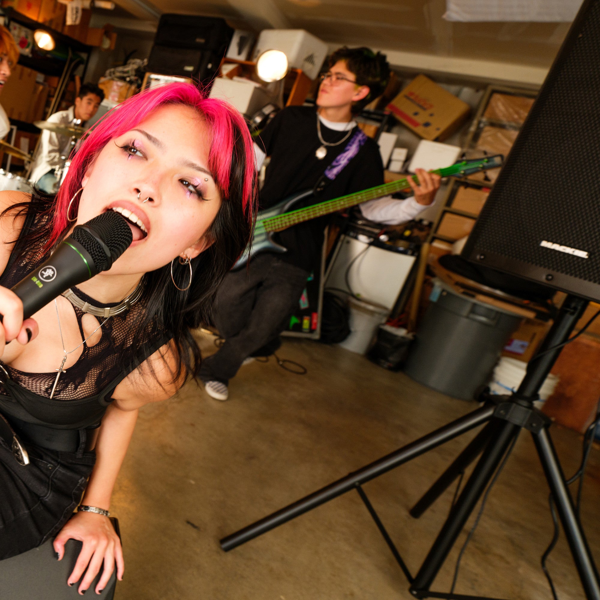 Band rehearsing in a garage with a Mackie Thrashv2 loudspeaker pole-mounted on a stand