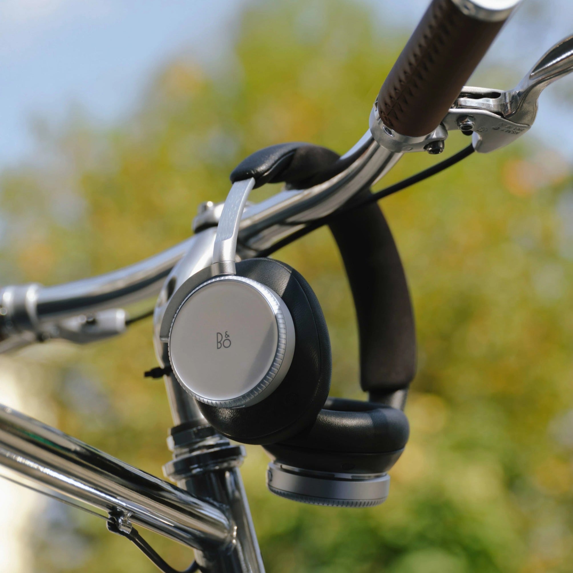 Wireless Bang & Olufsen Beoplay H100 headphones shown in a lifestyle setting with sleek, modern design and comfortable ear cushions.