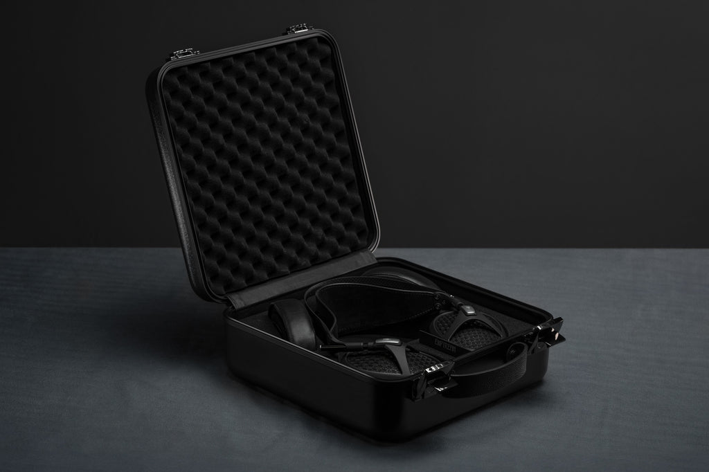 Open suitcase with Meze Audio Empyrean II wired headphones displayed inside, showcasing sleek design and premium craftsmanship.