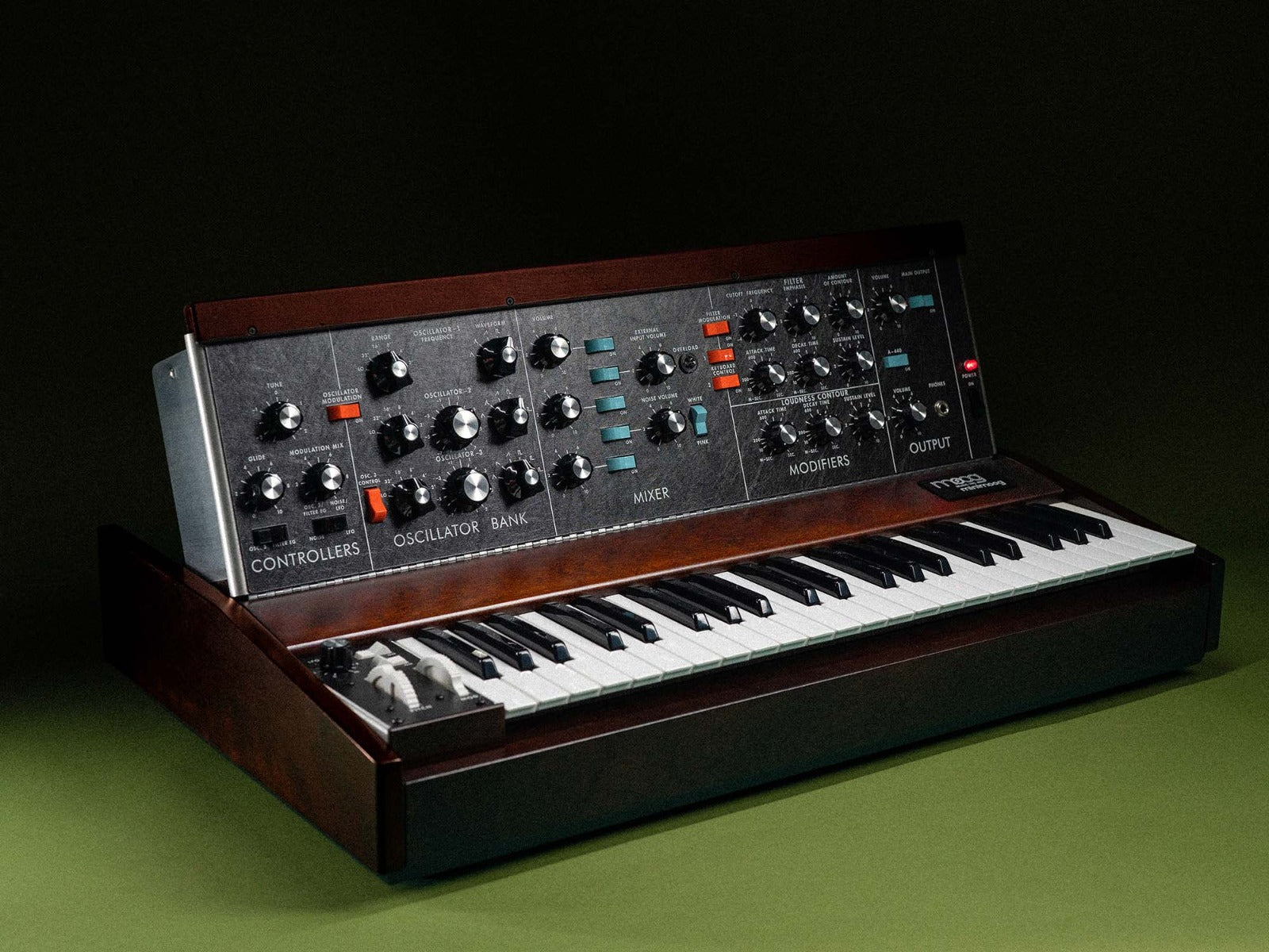 Moog Minimoog Model D synthesizer with vintage-style controls and wood side panels, viewed from a slight angle.
