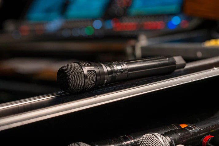 Shure Nexadyne 8/C dynamic microphone with a rugged design, shown in an outdoor environment for professional audio use.