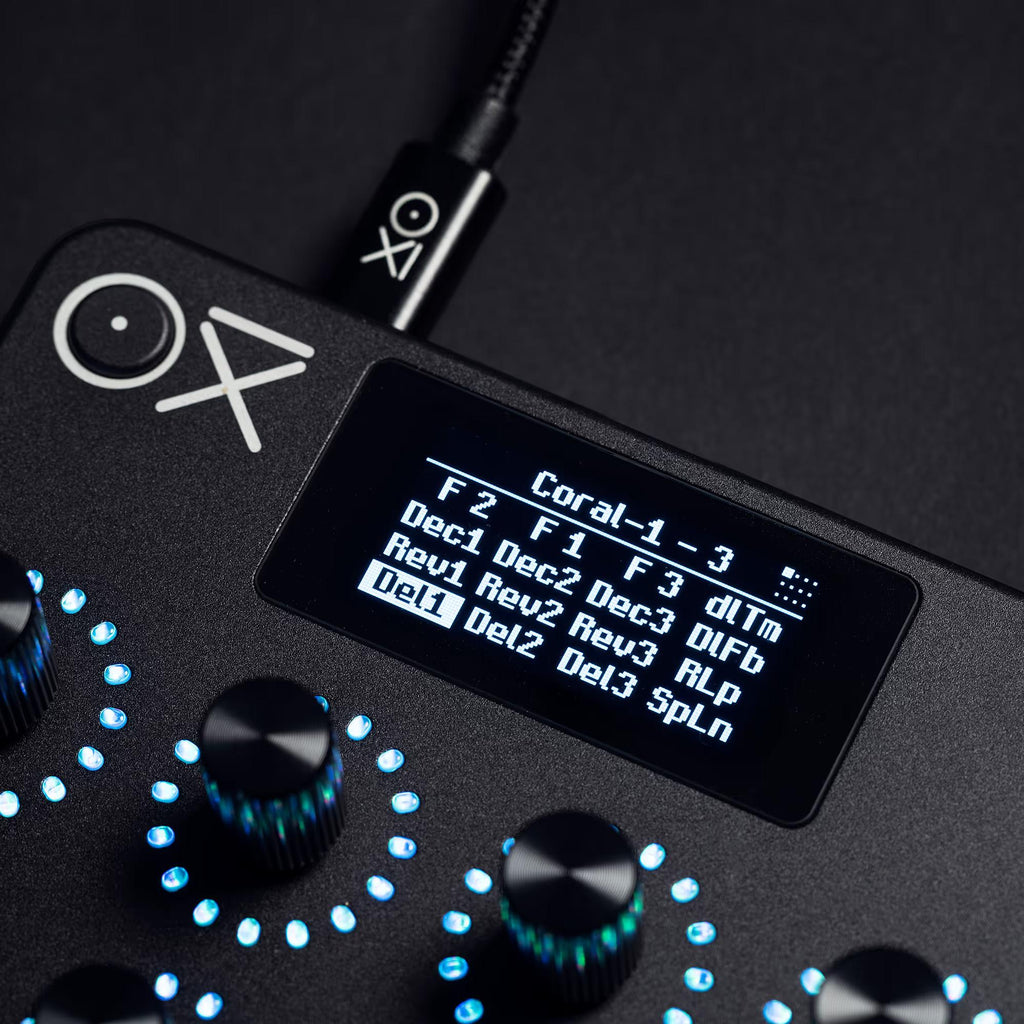 OXI Instruments E16 MIDI controller featuring various knobs and pads on a sleek black surface.
