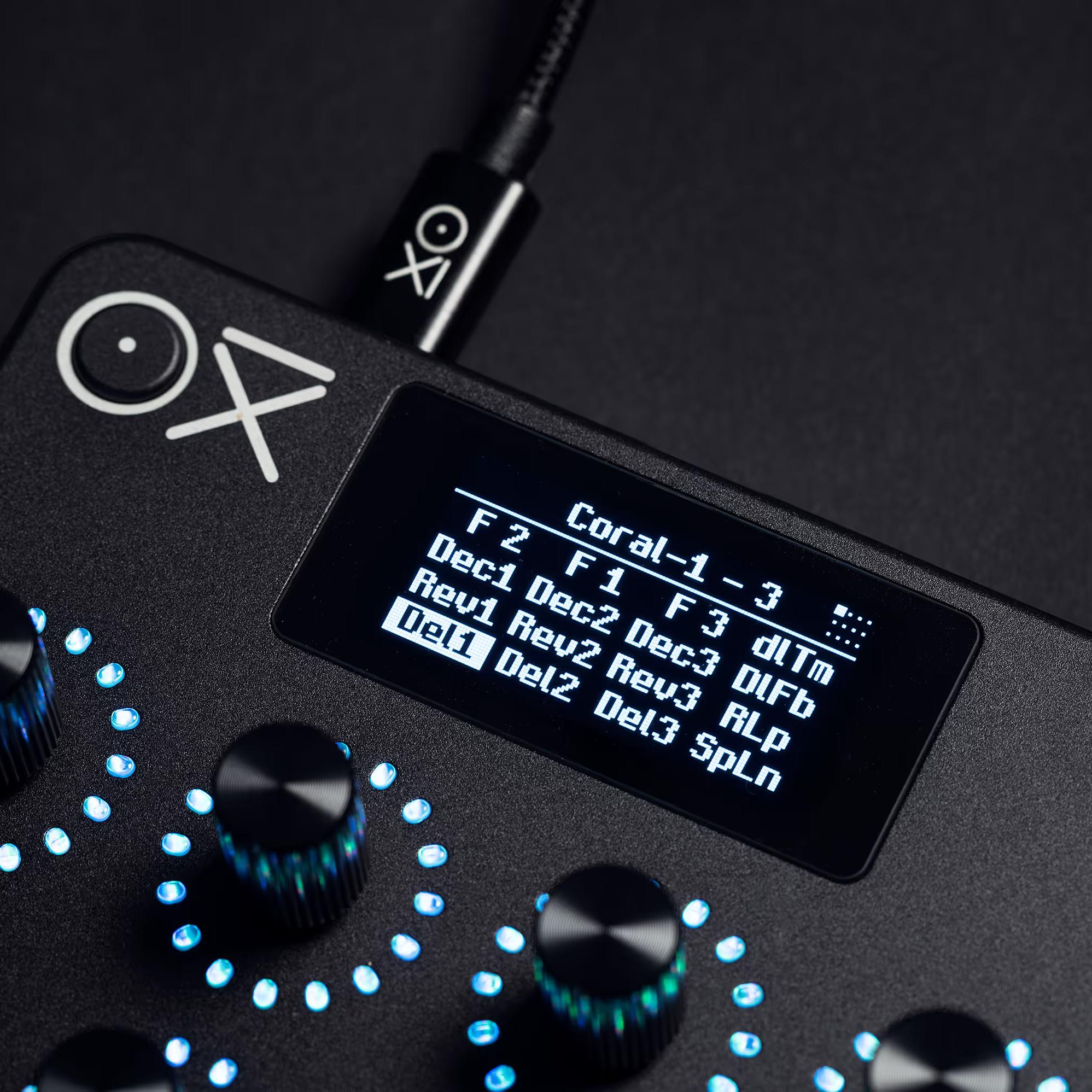 OXI Instruments E16 MIDI controller featuring various knobs and pads on a sleek black surface.
