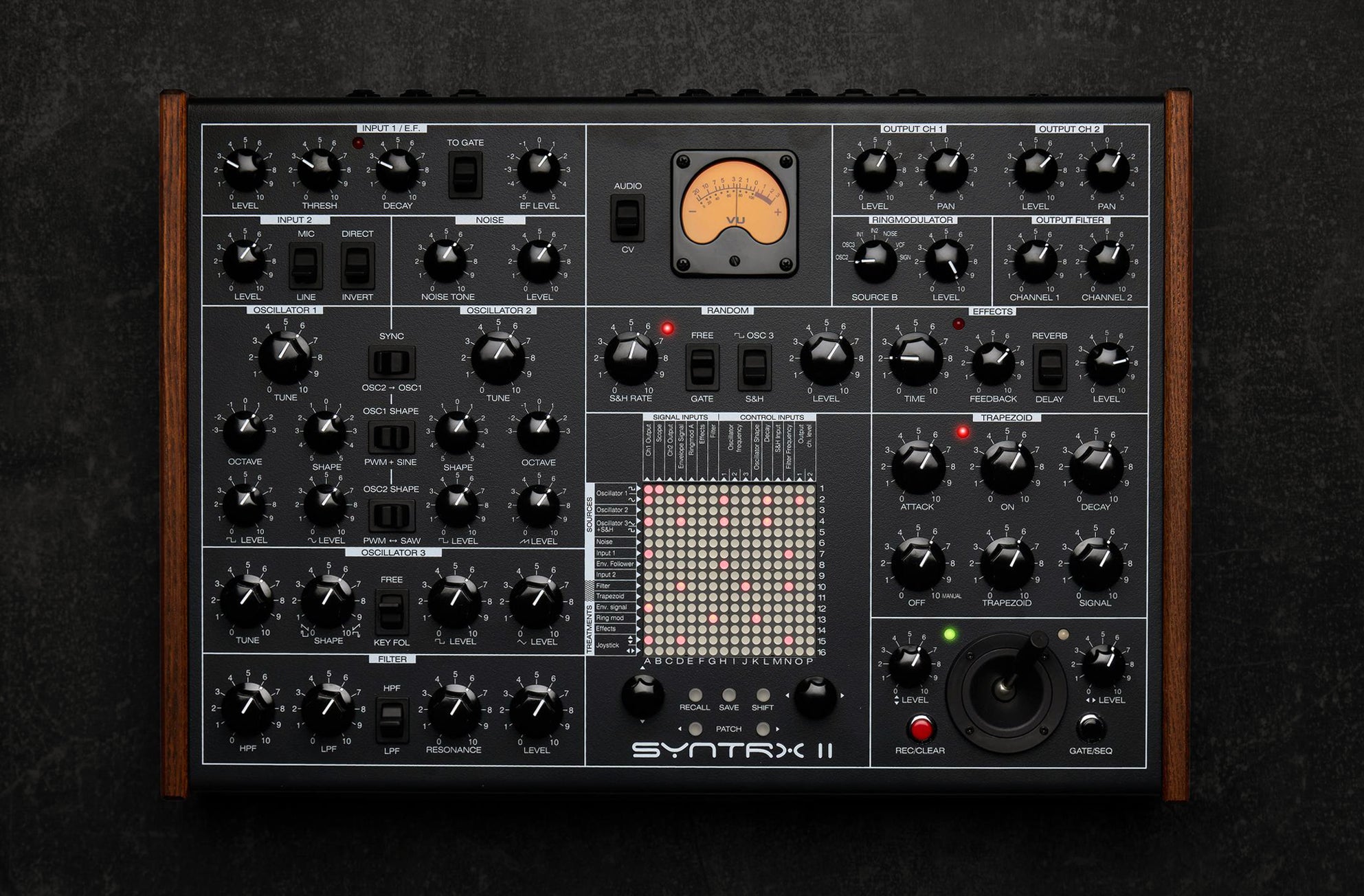 Erica Synths SYNTRX II desktop synthesizer with knobs, buttons, and OLED display on a black surface.