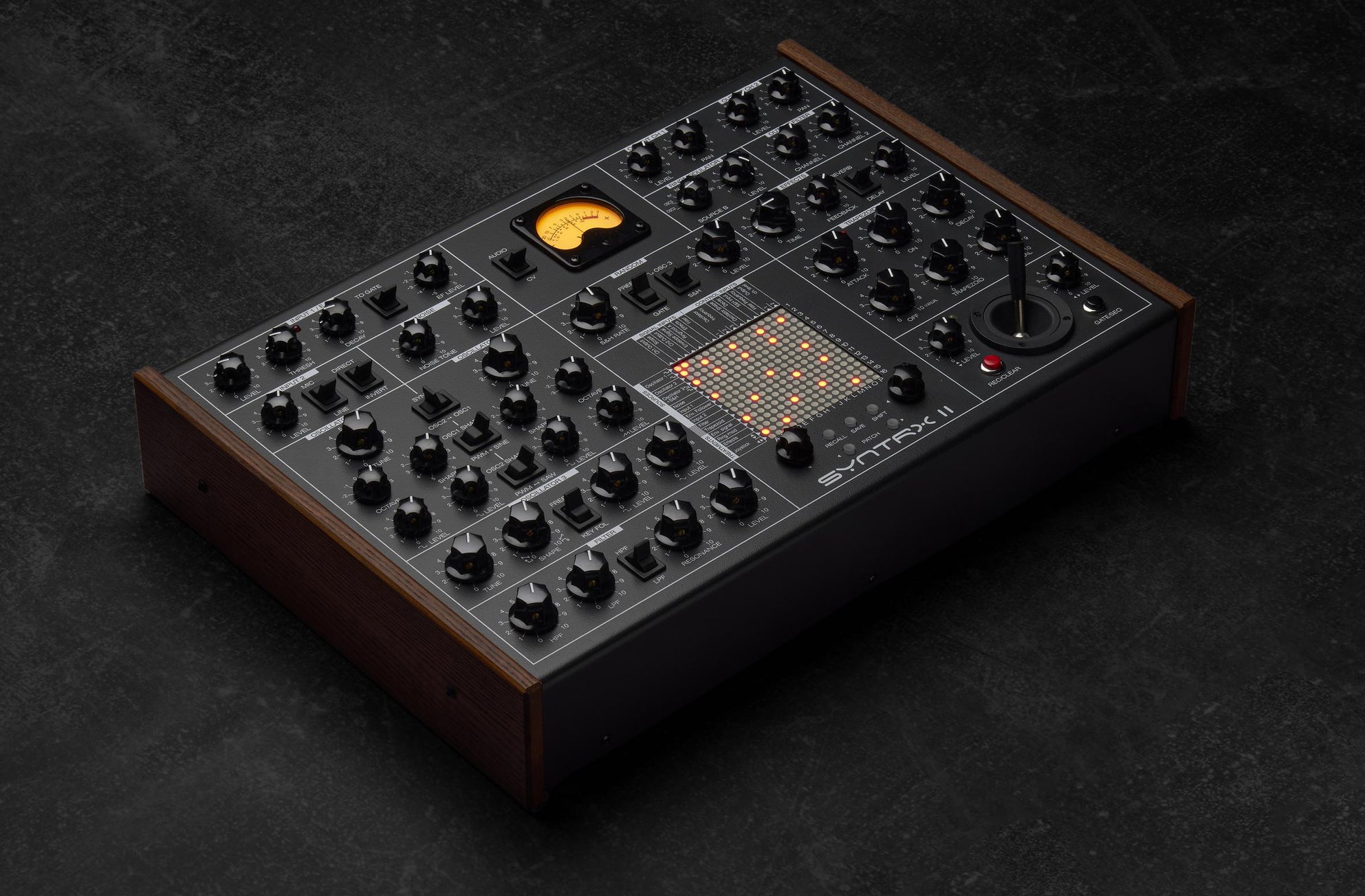 Erica Synths SYNTRX II desktop synthesizer with knobs and patch points on a black panel, showcasing its electronic interface.