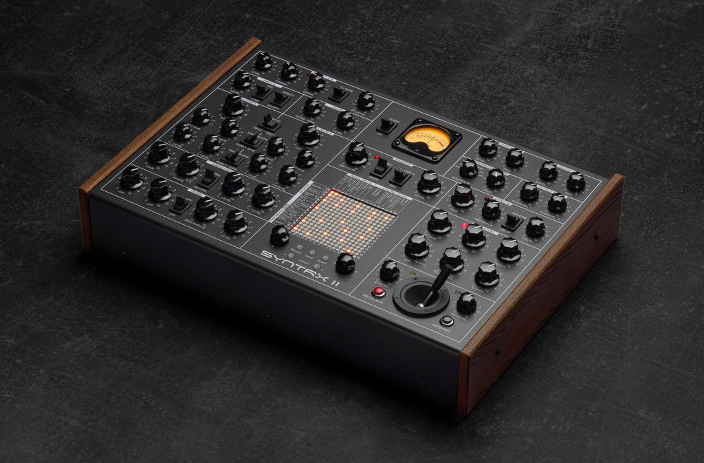 Erica Synths SYNTRX II desktop synthesizer with knobs, buttons, and display, showing its compact electronic music production interface.