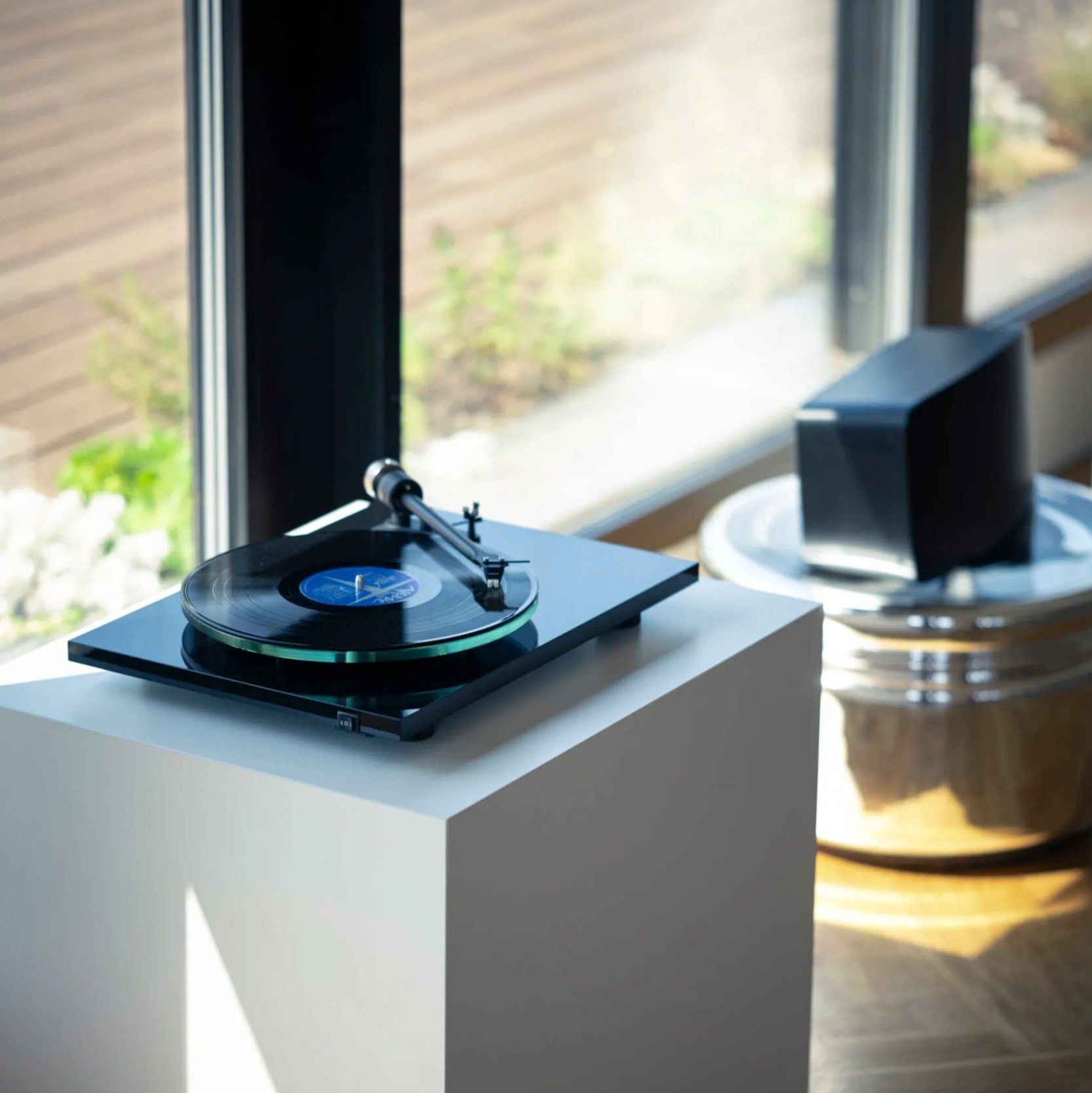 Pro-Ject T2 W turntable with wooden plinth and tonearm, set in a stylish modern living room environment.