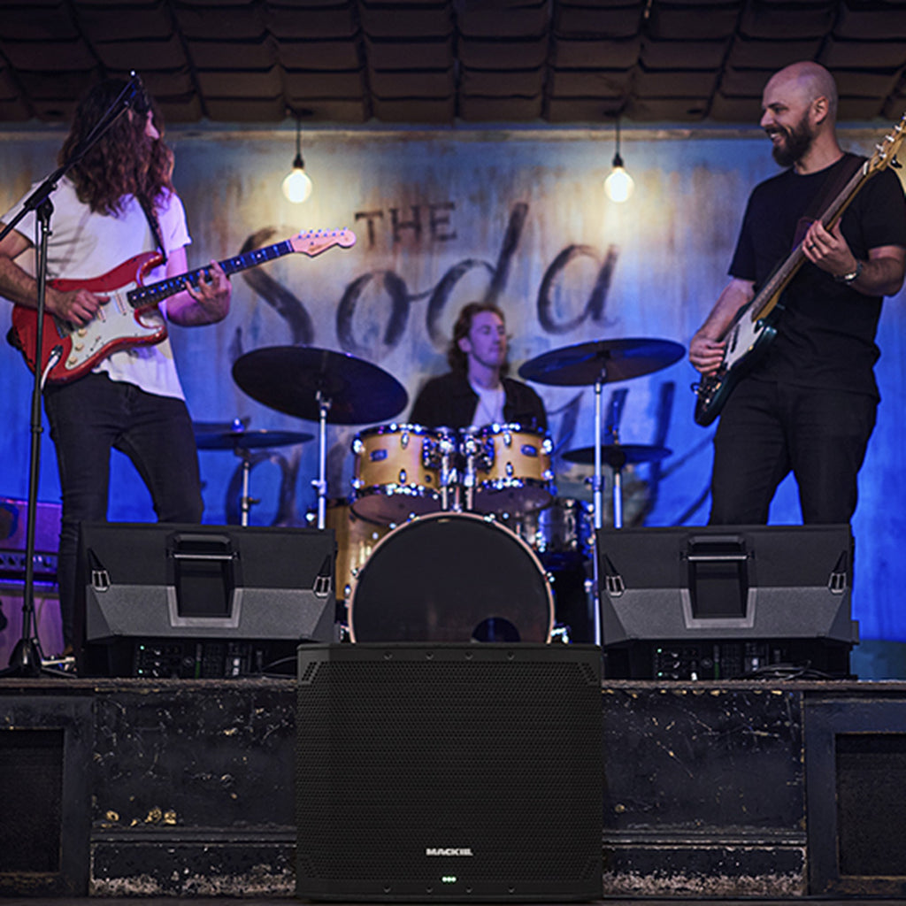 Mackie Thump15Sv4 active subwoofer on stage, showcasing its large speaker cone and robust black enclosure for powerful bass sound.