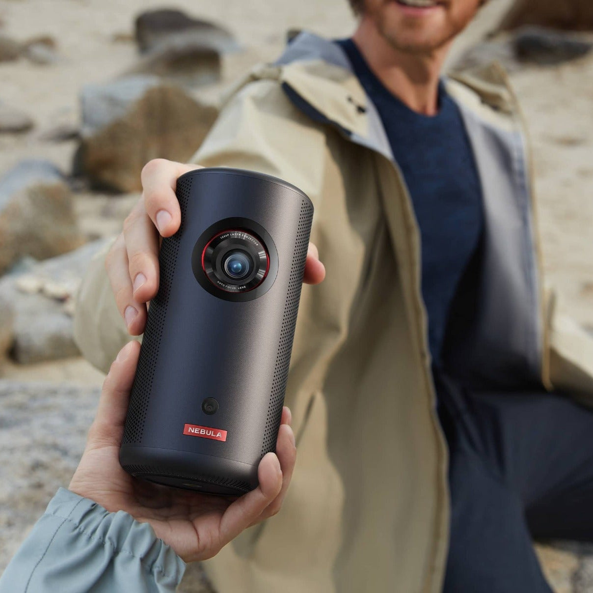 Nebula Capsule 3 Laser projector showing a bright, colorful image on a wall, compact design with lens and control buttons visible.