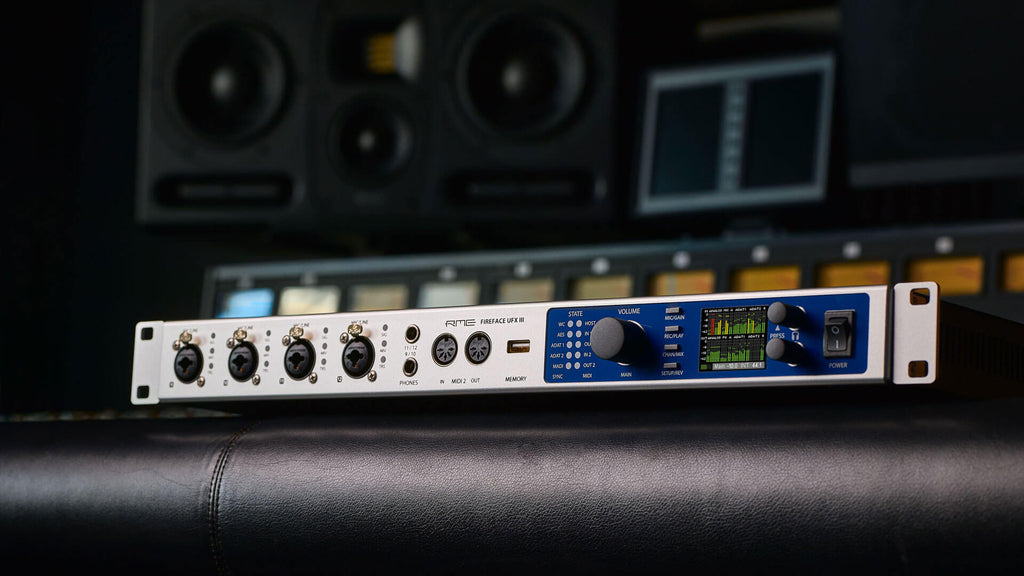 RME Fireface UFX III audio interface with multiple input and output connectors, control knobs, and display screen.