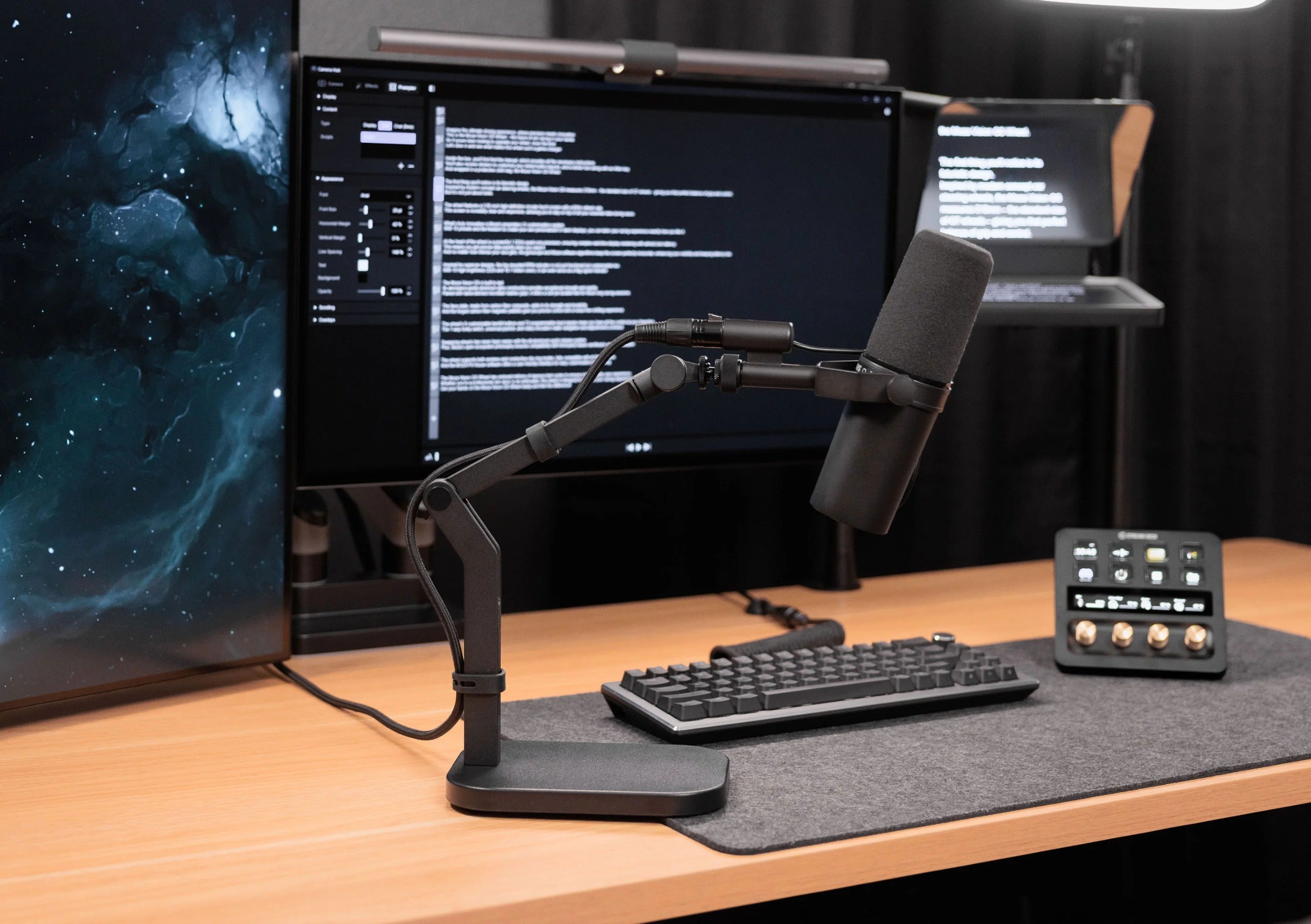 Elgato Wave Desk Stand holding a desktop microphone on a workspace with a laptop and headphones.